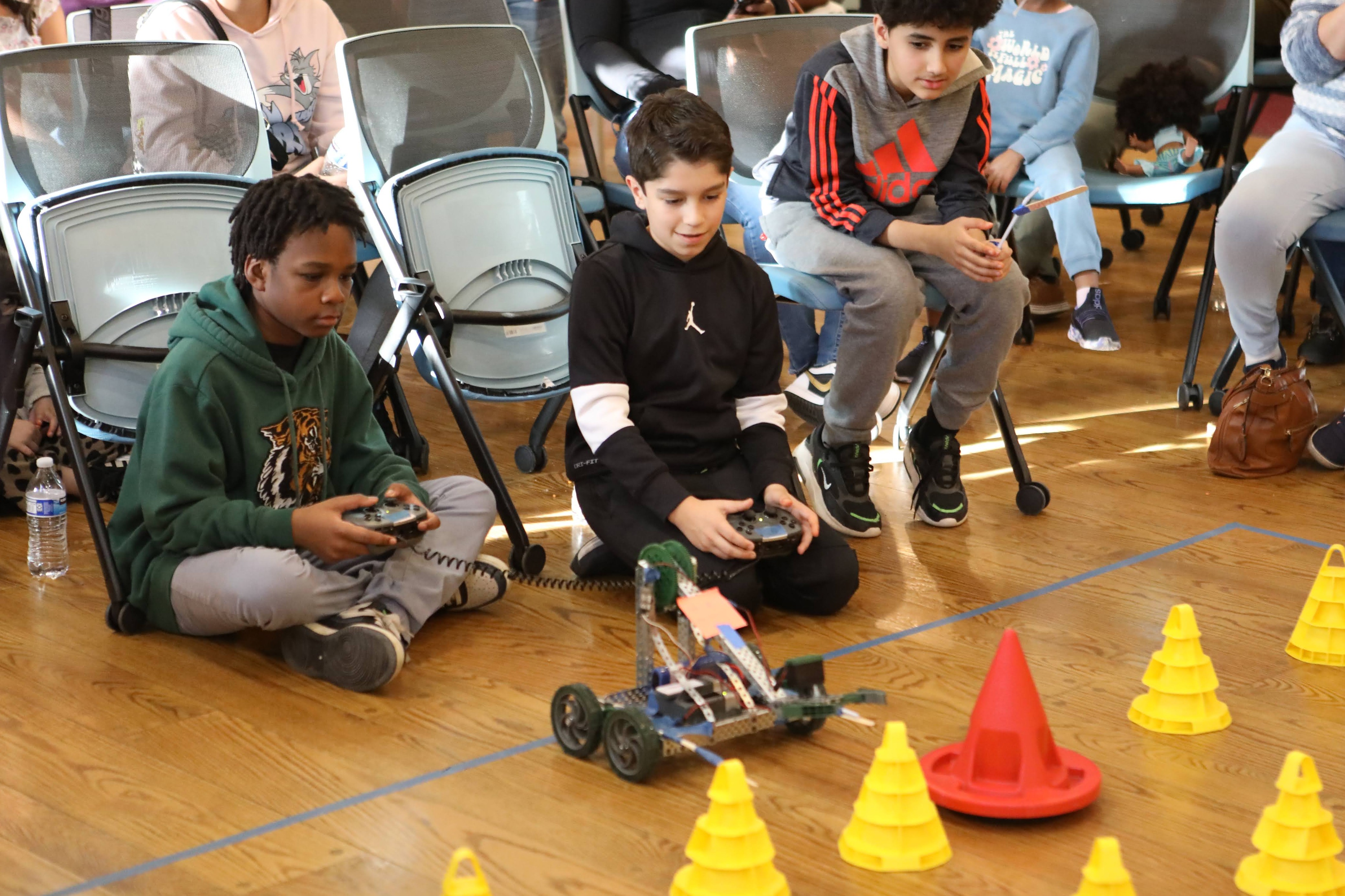 Each with a remote controller in hand, two Pathways Scholars work together to operate their robot in a cone-stacking competition.