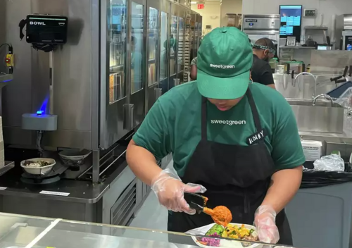 Sweetgreen worker prepares bowl on kitchen counter