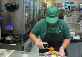 Sweetgreen worker prepares bowl on kitchen counter