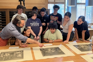 An instructor points out a feature of an illustration to smiling a group of smiling students.